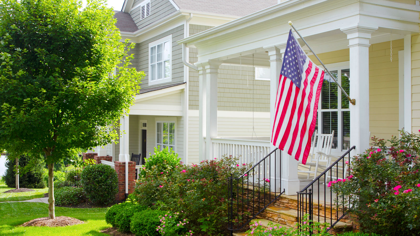 front porch of a house, white, with an American flag and lawn